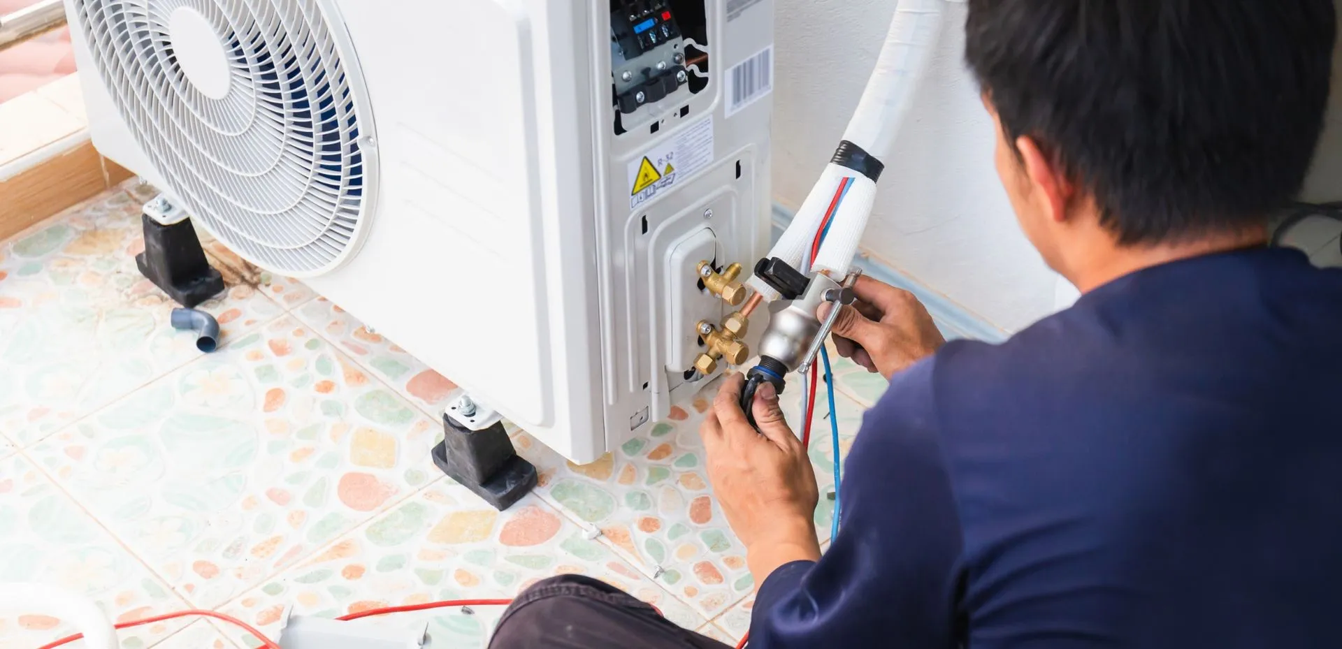Technician cleaning outdoor air conditioning unit