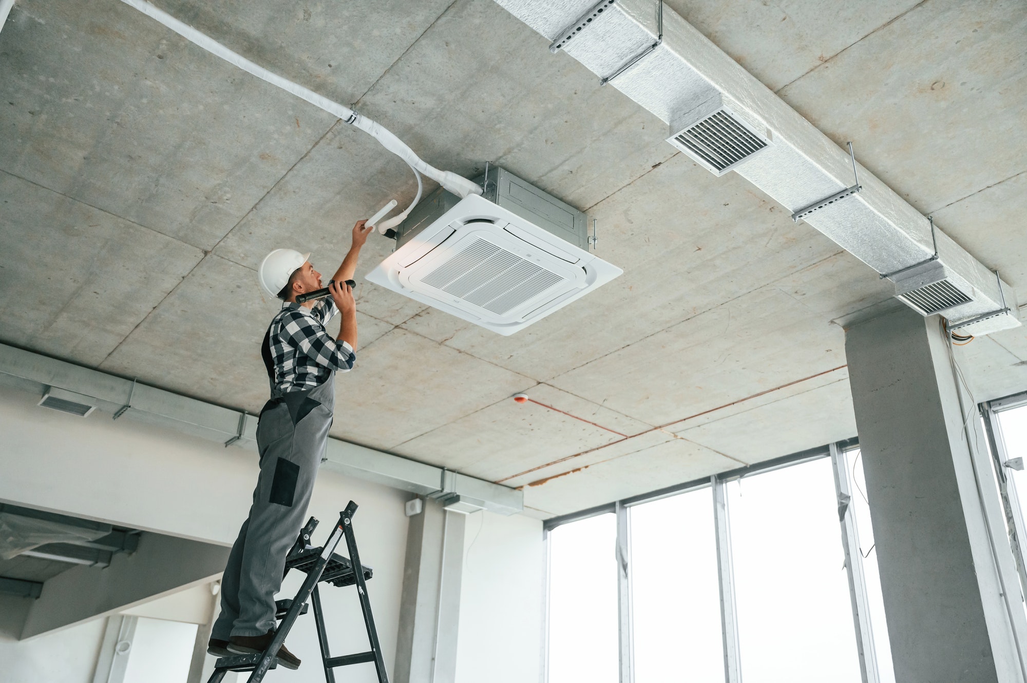 Engineer servicing ceiling-mounted air conditioning unit